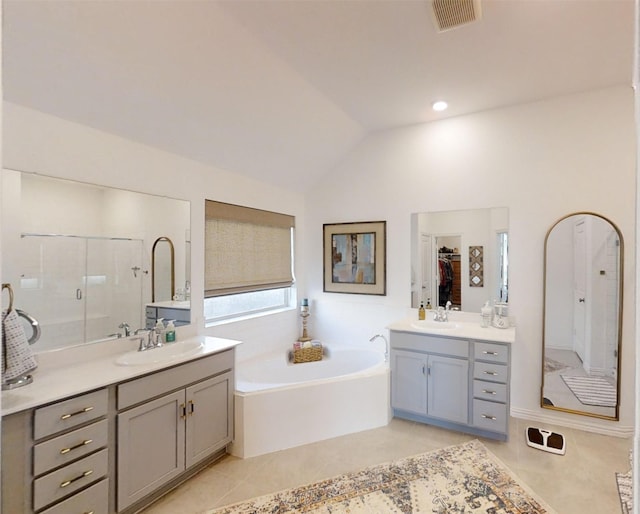 bathroom with tile patterned flooring, shower with separate bathtub, vaulted ceiling, and vanity