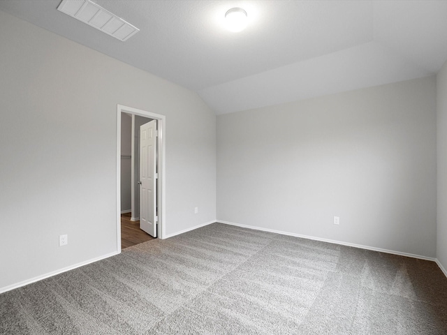 carpeted empty room featuring vaulted ceiling