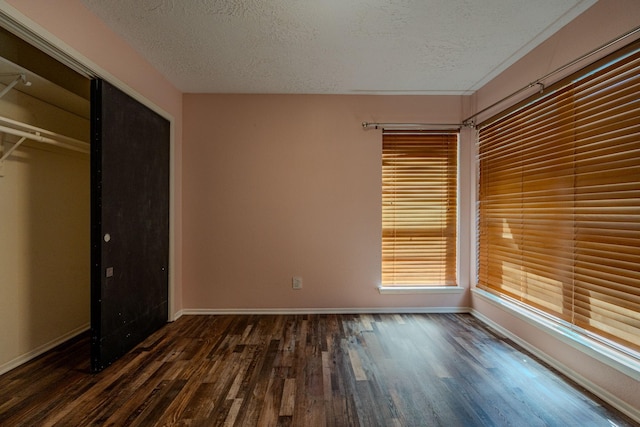 unfurnished bedroom with a textured ceiling, a closet, and dark hardwood / wood-style floors