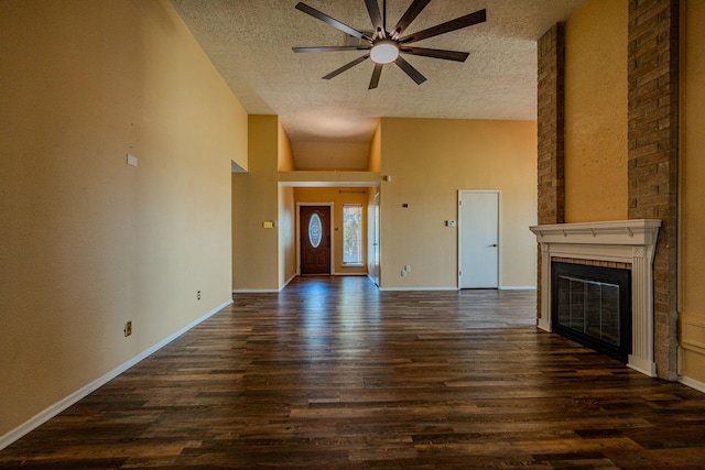 unfurnished living room with a brick fireplace, a textured ceiling, ceiling fan, and dark hardwood / wood-style flooring