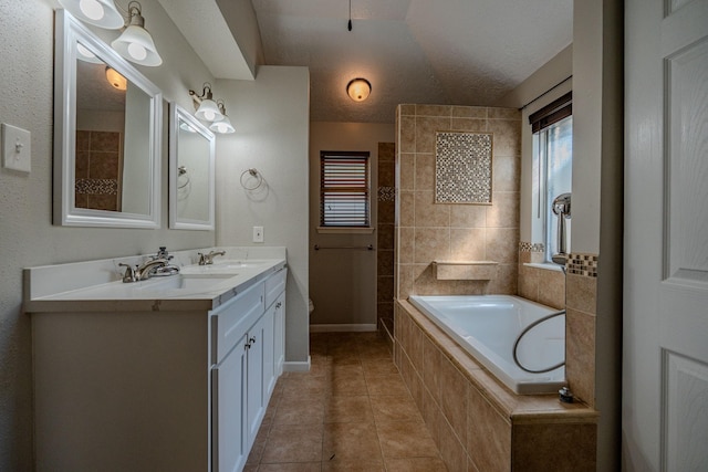 bathroom with a textured ceiling, tile patterned floors, tiled tub, and vanity