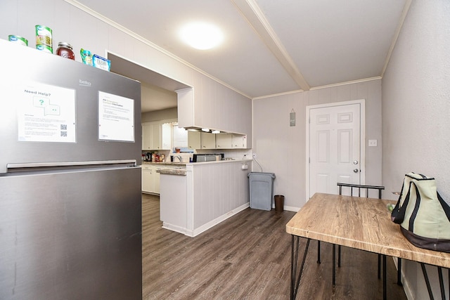 kitchen with dark wood-type flooring, stainless steel fridge, ornamental molding, white cabinets, and kitchen peninsula