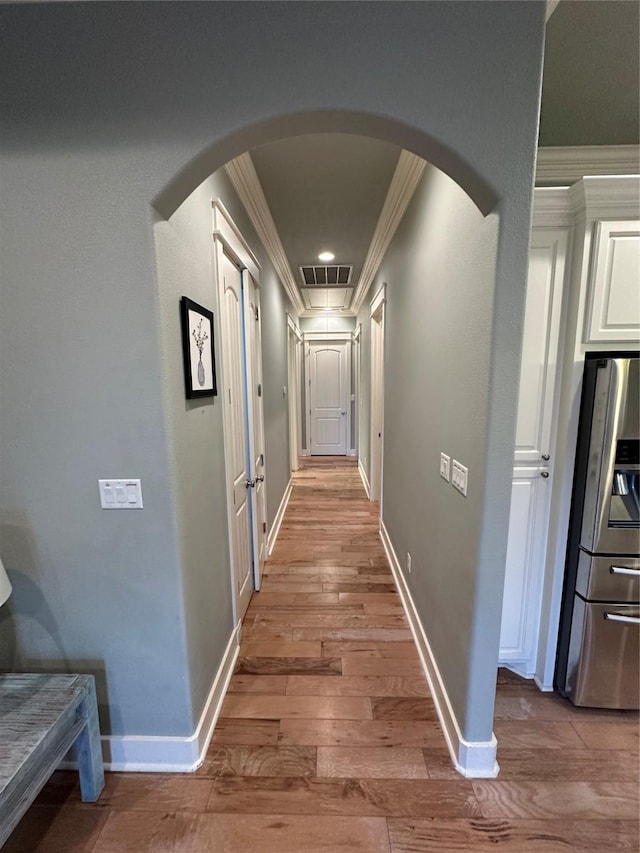 hall with ornamental molding and light wood-type flooring