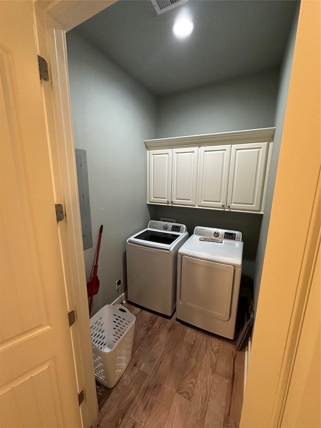 laundry area with cabinets, electric panel, independent washer and dryer, and light hardwood / wood-style flooring