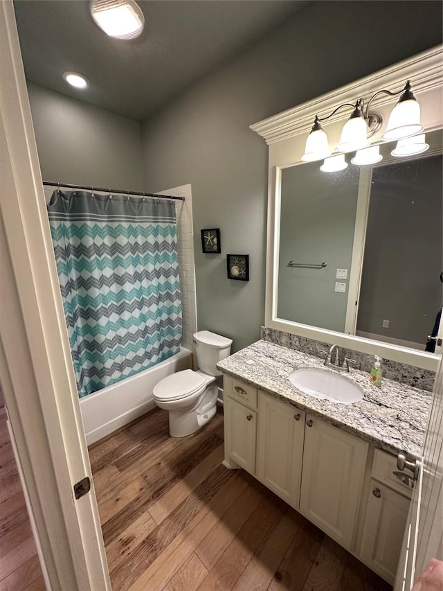 full bathroom featuring hardwood / wood-style flooring, vanity, toilet, and shower / bath combination with curtain