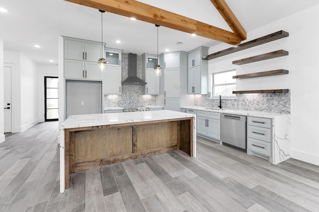 kitchen featuring dishwasher, a spacious island, light stone countertops, wall chimney range hood, and pendant lighting