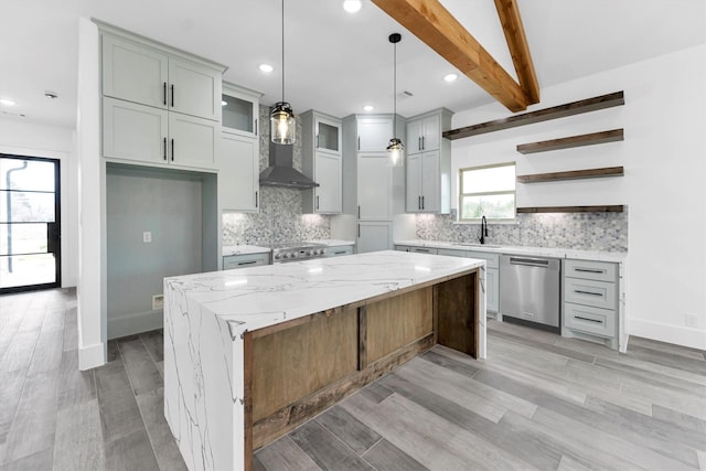 kitchen featuring a center island, beamed ceiling, light stone counters, decorative light fixtures, and stainless steel dishwasher