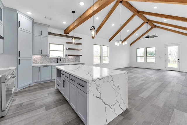 kitchen with hanging light fixtures, a spacious island, gray cabinets, high end stove, and vaulted ceiling with beams