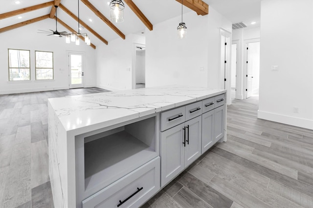 kitchen featuring light hardwood / wood-style flooring, decorative light fixtures, lofted ceiling with beams, and light stone countertops