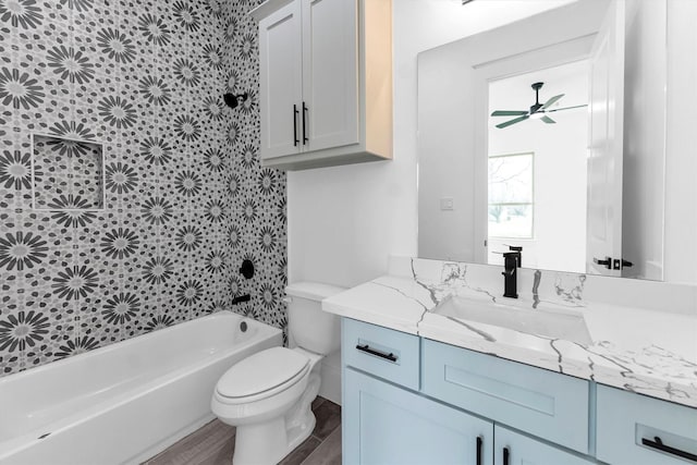 full bathroom with washtub / shower combination, toilet, vanity, ceiling fan, and hardwood / wood-style flooring