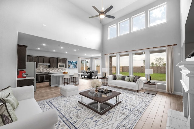 living room featuring ceiling fan, a towering ceiling, and a high end fireplace