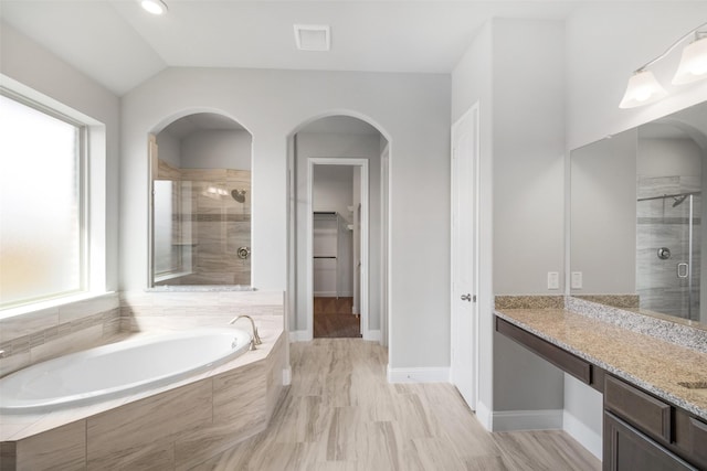 bathroom featuring vaulted ceiling, plus walk in shower, and vanity