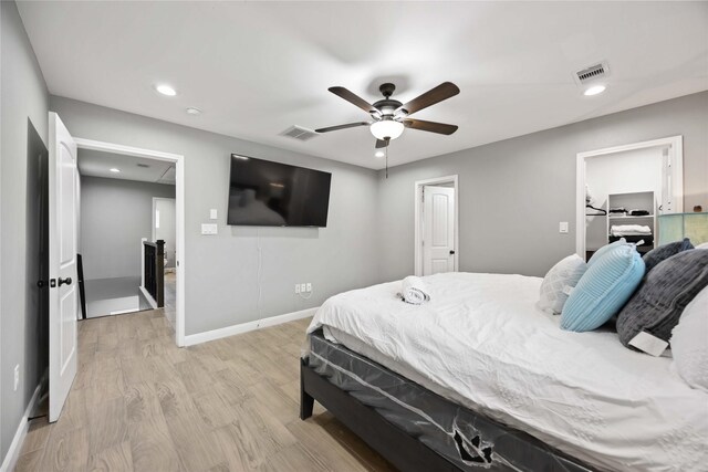 bedroom featuring a walk in closet, ceiling fan, light hardwood / wood-style flooring, and a closet