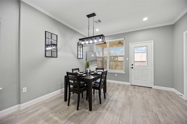 dining space featuring light wood-type flooring and crown molding