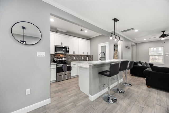 kitchen with a center island with sink, stainless steel appliances, hanging light fixtures, a breakfast bar, and white cabinetry