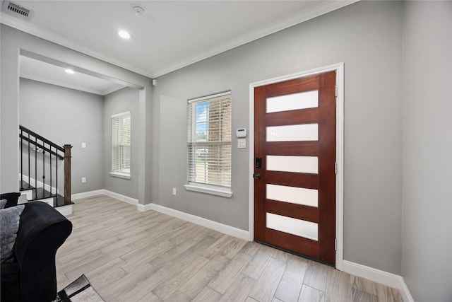 entryway with ornamental molding and light hardwood / wood-style flooring