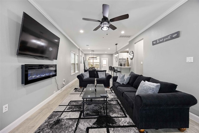 living room with ceiling fan, light wood-type flooring, and crown molding