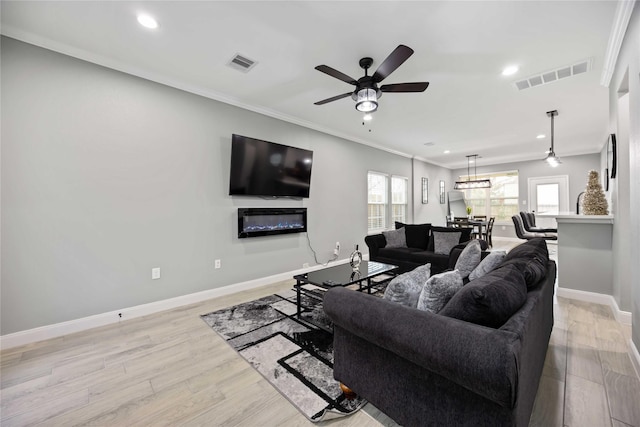 living room featuring ceiling fan, light hardwood / wood-style flooring, and crown molding