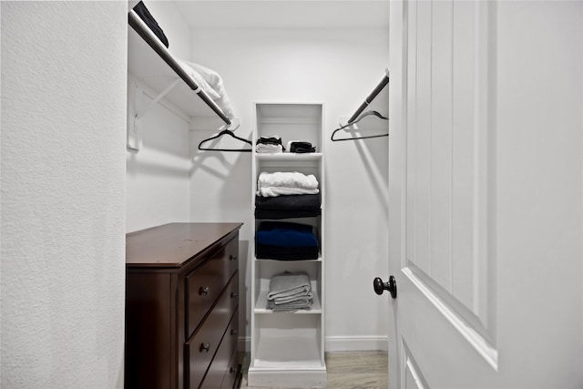 walk in closet with light hardwood / wood-style flooring