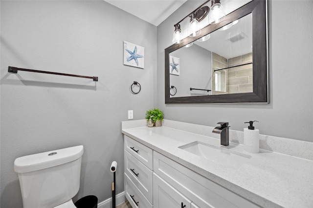 bathroom featuring toilet, a tile shower, and vanity