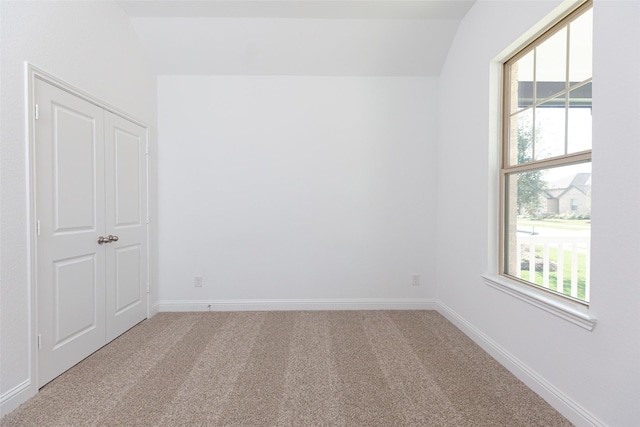 carpeted empty room featuring vaulted ceiling and a wealth of natural light