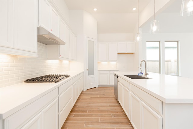 kitchen featuring hanging light fixtures, stainless steel appliances, a kitchen island with sink, white cabinets, and sink