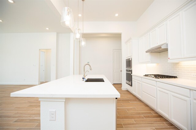 kitchen featuring white cabinets, stainless steel gas stovetop, an island with sink, and sink