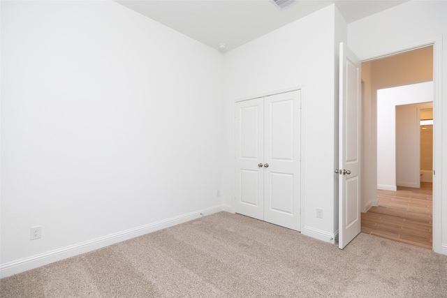 unfurnished bedroom with a closet and light colored carpet