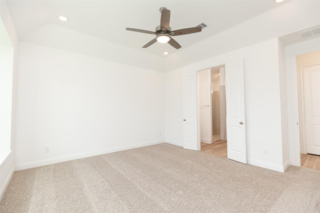 unfurnished bedroom featuring a raised ceiling, light colored carpet, and ceiling fan