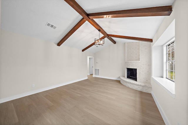 unfurnished living room featuring light hardwood / wood-style floors, a brick fireplace, lofted ceiling with beams, and an inviting chandelier