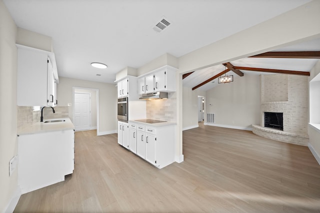 kitchen featuring sink, stainless steel oven, a fireplace, and decorative backsplash