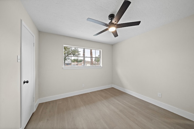 spare room featuring ceiling fan, light wood-type flooring, and a textured ceiling