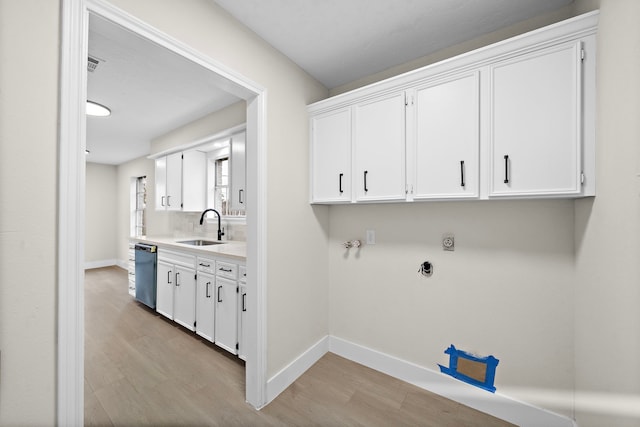 laundry room featuring light hardwood / wood-style floors, cabinets, electric dryer hookup, and sink