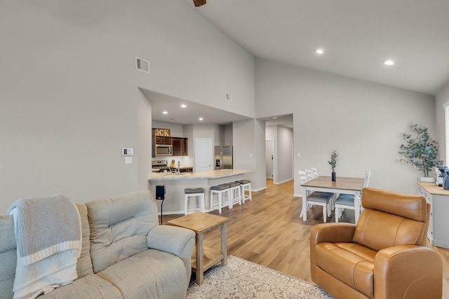 living room with a high ceiling, light hardwood / wood-style floors, and sink