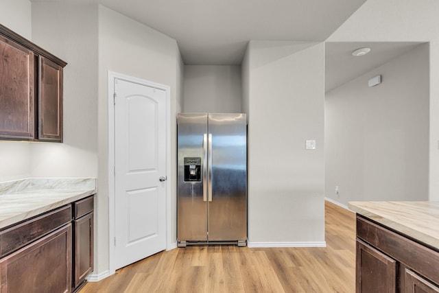 kitchen featuring stainless steel fridge, light hardwood / wood-style flooring, and dark brown cabinetry