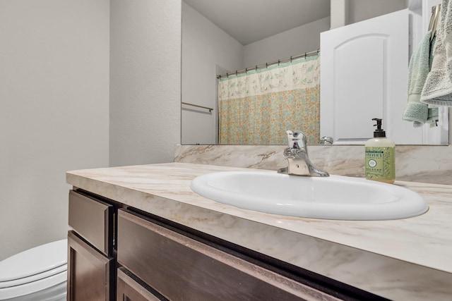 bathroom featuring walk in shower, vanity, and toilet