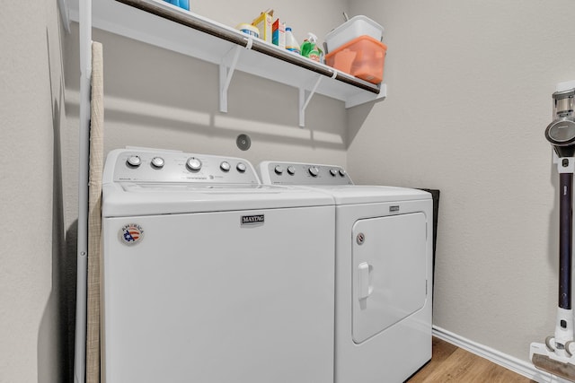 laundry area with light hardwood / wood-style floors and washer and clothes dryer