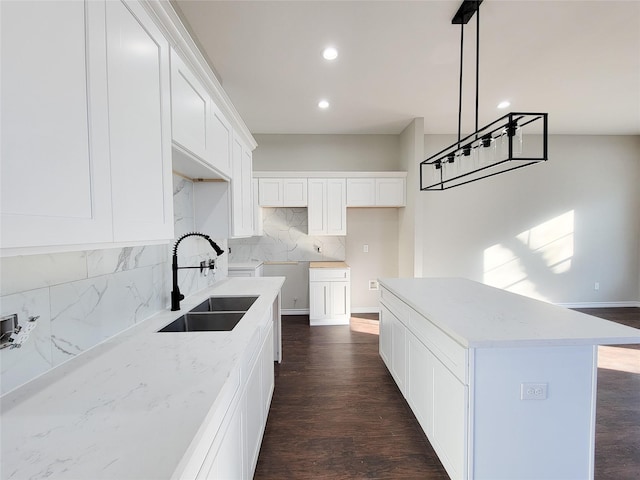 kitchen with sink, a kitchen island, white cabinets, and hanging light fixtures