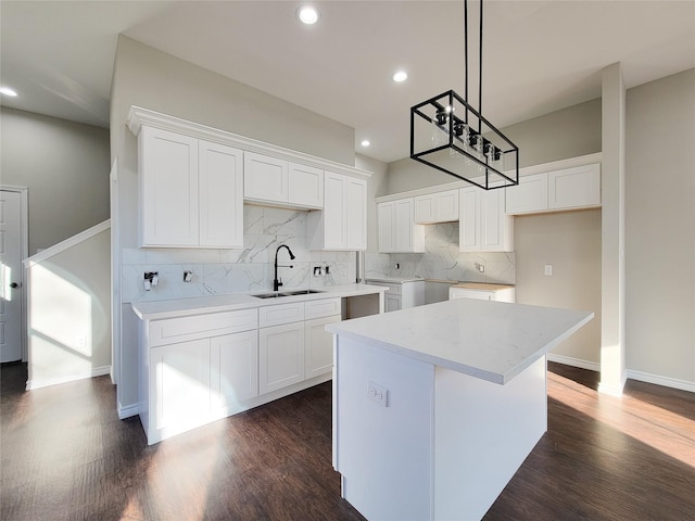 kitchen featuring dark wood-type flooring, a kitchen island, white cabinets, decorative light fixtures, and sink