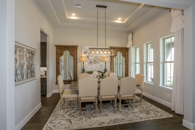 dining area with dark hardwood / wood-style floors and a tray ceiling