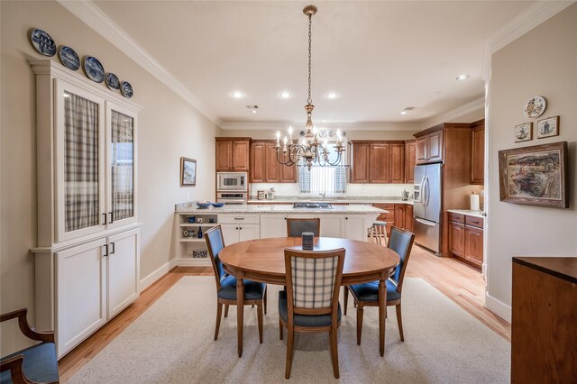 dining area featuring ornamental molding, a notable chandelier, and light hardwood / wood-style flooring