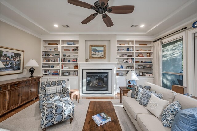 living room with ceiling fan, crown molding, and built in features