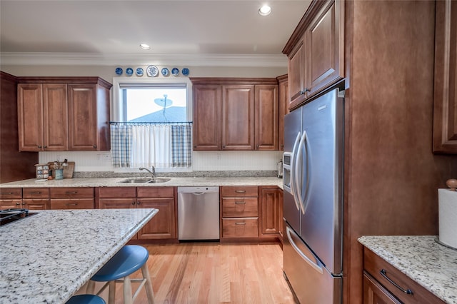 kitchen with appliances with stainless steel finishes, a kitchen breakfast bar, crown molding, and sink