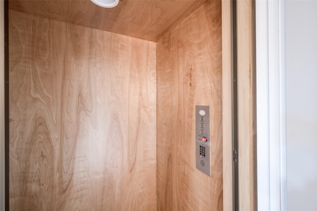 interior details with elevator, wood walls, and wooden ceiling