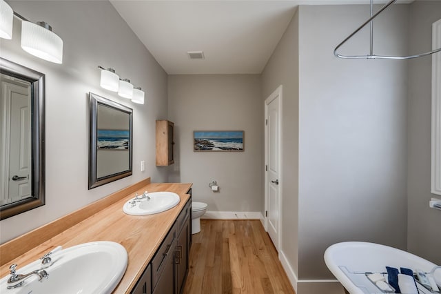 bathroom featuring wood-type flooring, vanity, and toilet