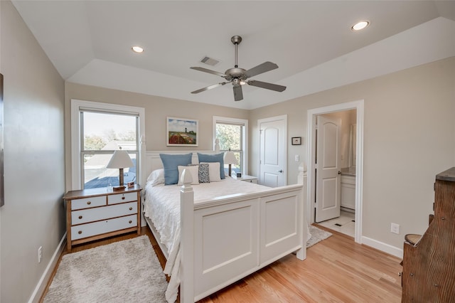 bedroom with vaulted ceiling, ceiling fan, light hardwood / wood-style flooring, and connected bathroom