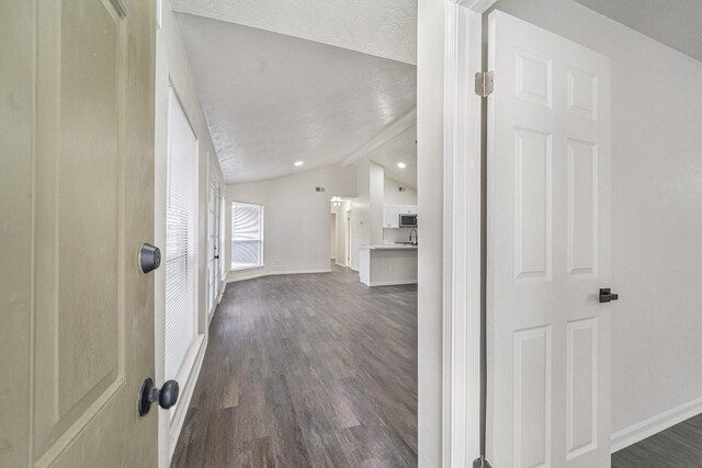 hallway with lofted ceiling, a textured ceiling, and dark hardwood / wood-style floors