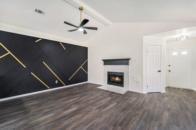 unfurnished living room with ceiling fan, dark wood-type flooring, a tiled fireplace, and vaulted ceiling with beams