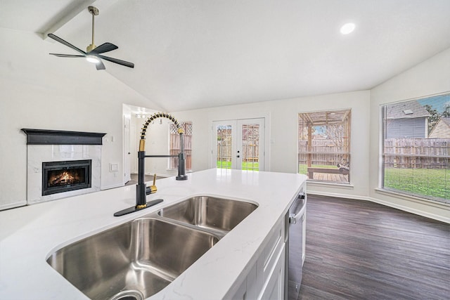 kitchen featuring a tile fireplace, vaulted ceiling with beams, dark hardwood / wood-style floors, sink, and stainless steel dishwasher