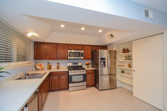 kitchen with sink, stainless steel appliances, lofted ceiling, and a tray ceiling